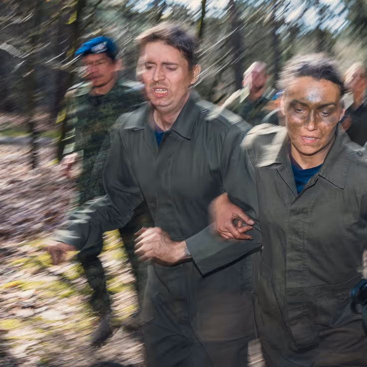 Een groepje cadetten rent met een waterfles in de hand door het bos.