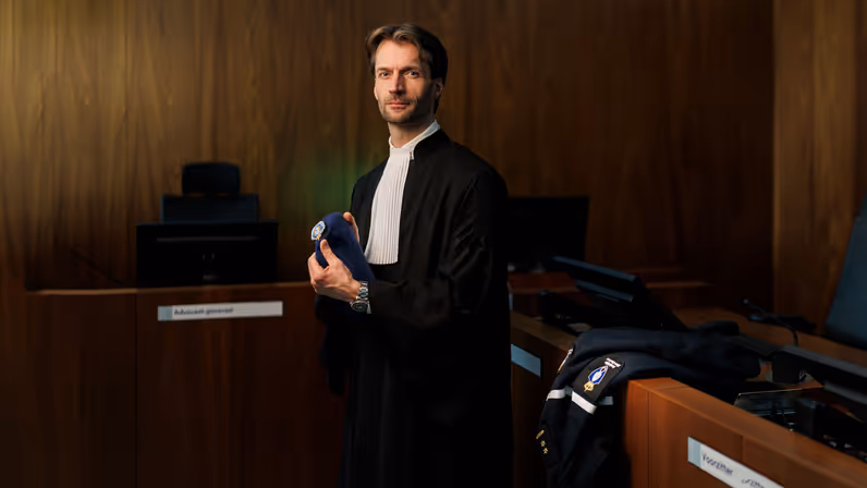 Portret van luitenant-kolonel Sébas in een toga en met baret KMar in de hand.