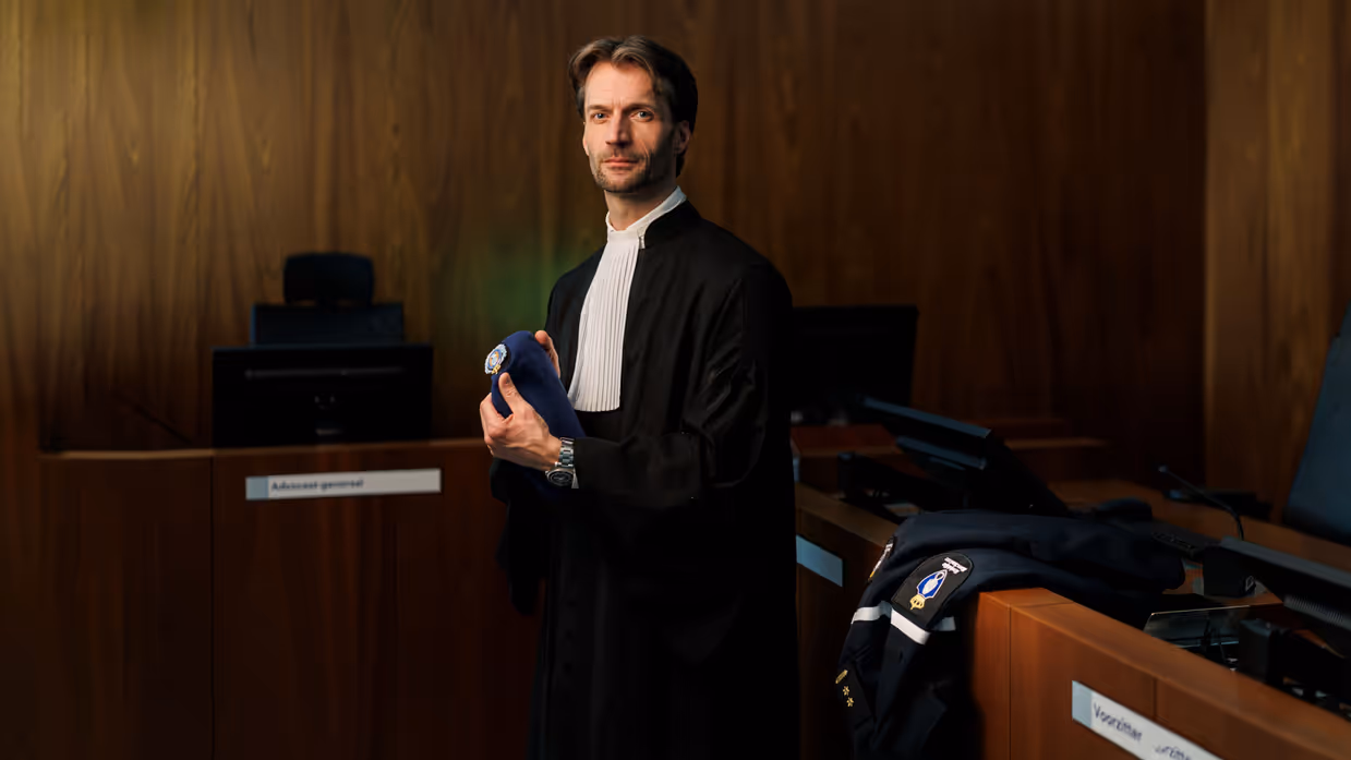 Portret van luitenant-kolonel Sébas in een toga en met baret KMar in de hand.