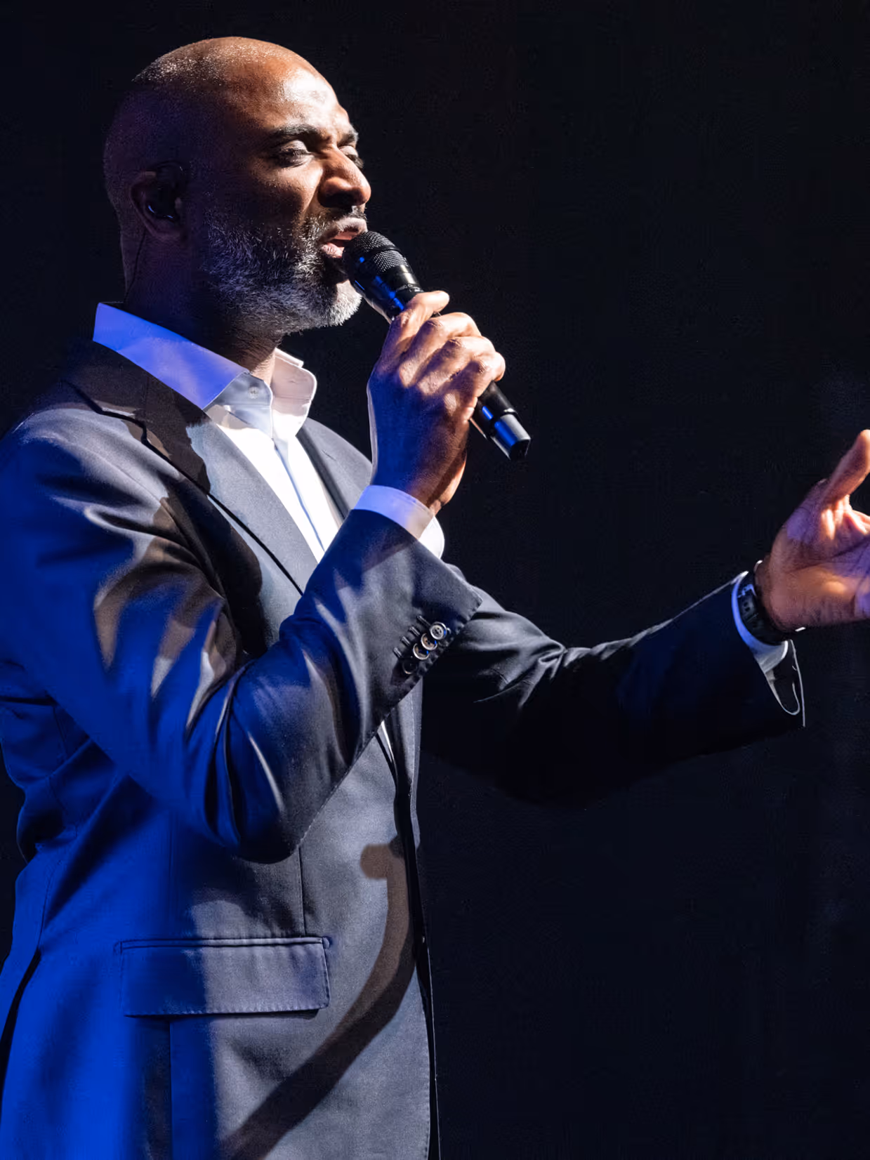 Diverse zangers en zangeressen voor op het podium met in de achtergrond het orkest met dirigent.