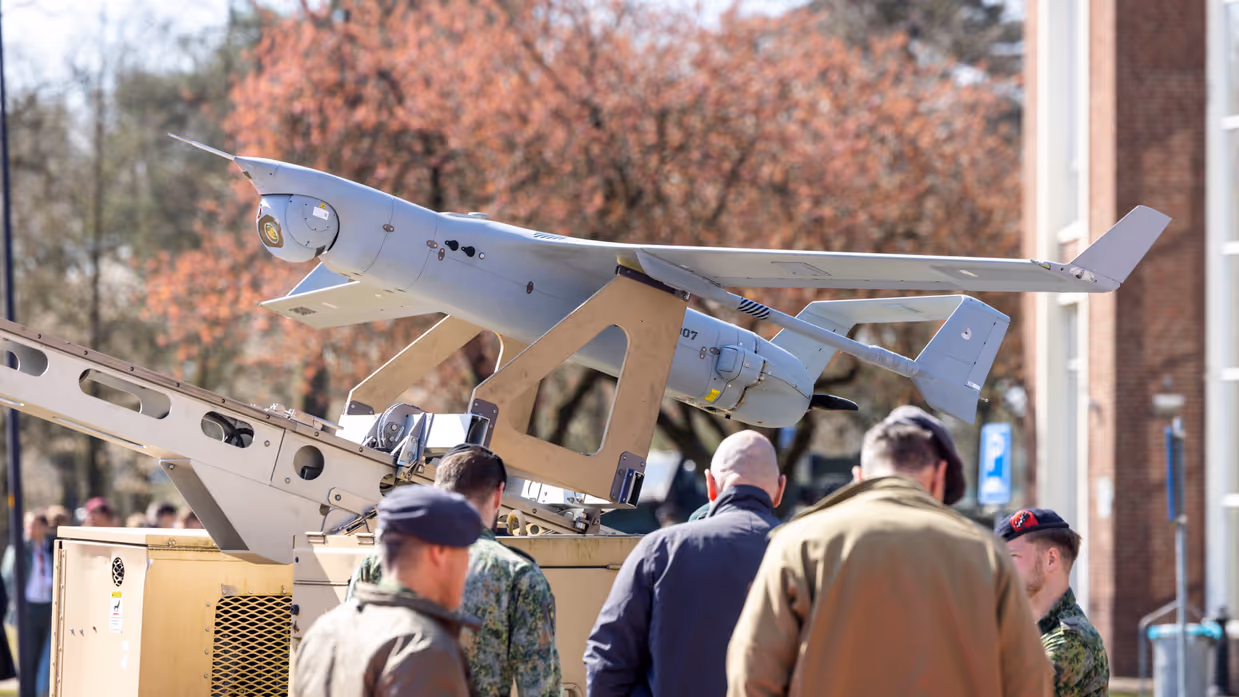 Militairen en bezoekers bekijken een drone tijdens een demonstratie. 