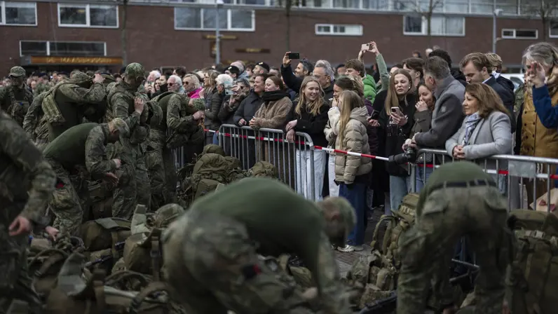 De nieuwe mariniers hangen hun rugzak af en leggen hun wapen, terwijl familie en vrienden bewonderend toekijken.