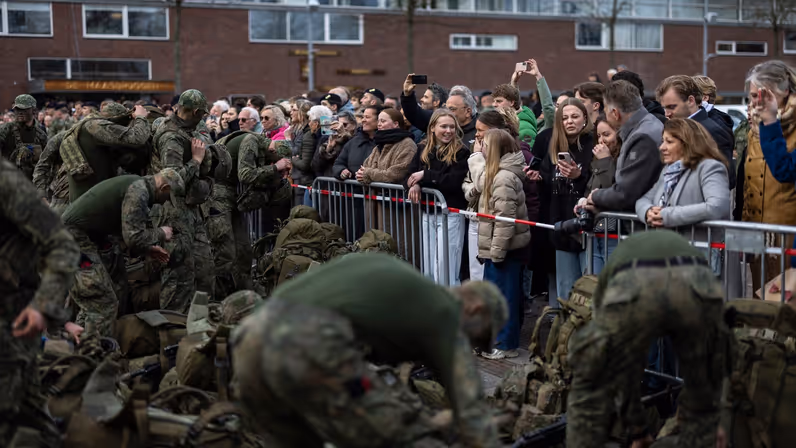 De nieuwe mariniers hangen hun rugzak af en leggen hun wapen, terwijl familie en vrienden bewonderend toekijken.