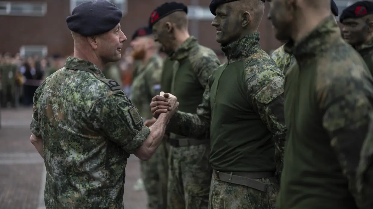 Korpsadjudant Rob Poesiat feliciteert een nieuwe marinier die net zijn nieuwe baret draagt, net als de mannen naast hem.