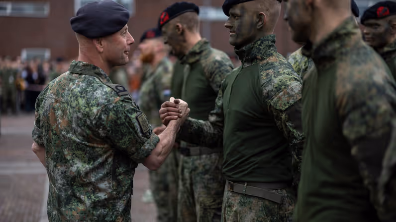 Korpsadjudant Rob Poesiat feliciteert een nieuwe marinier die net zijn nieuwe baret draagt, net als de mannen naast hem.