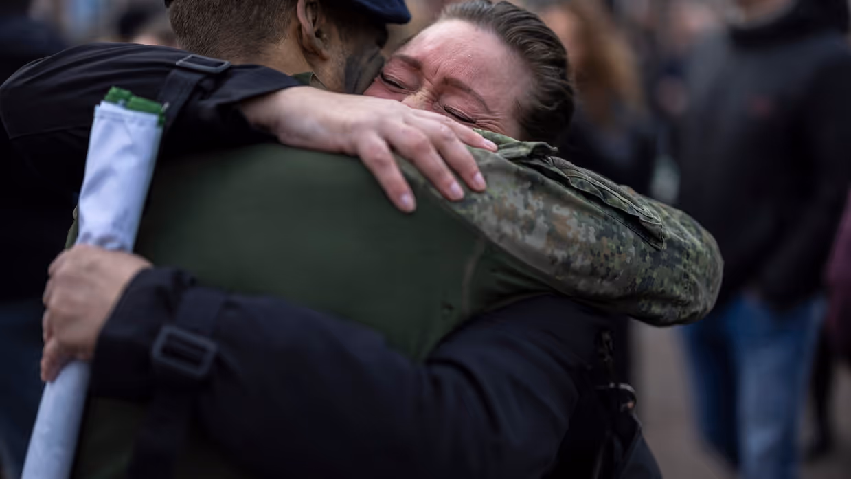 Alttekst: Een geëmotioneerde moeder omhelst haar zoon die zojuist zijn baret heeft gekregen. 