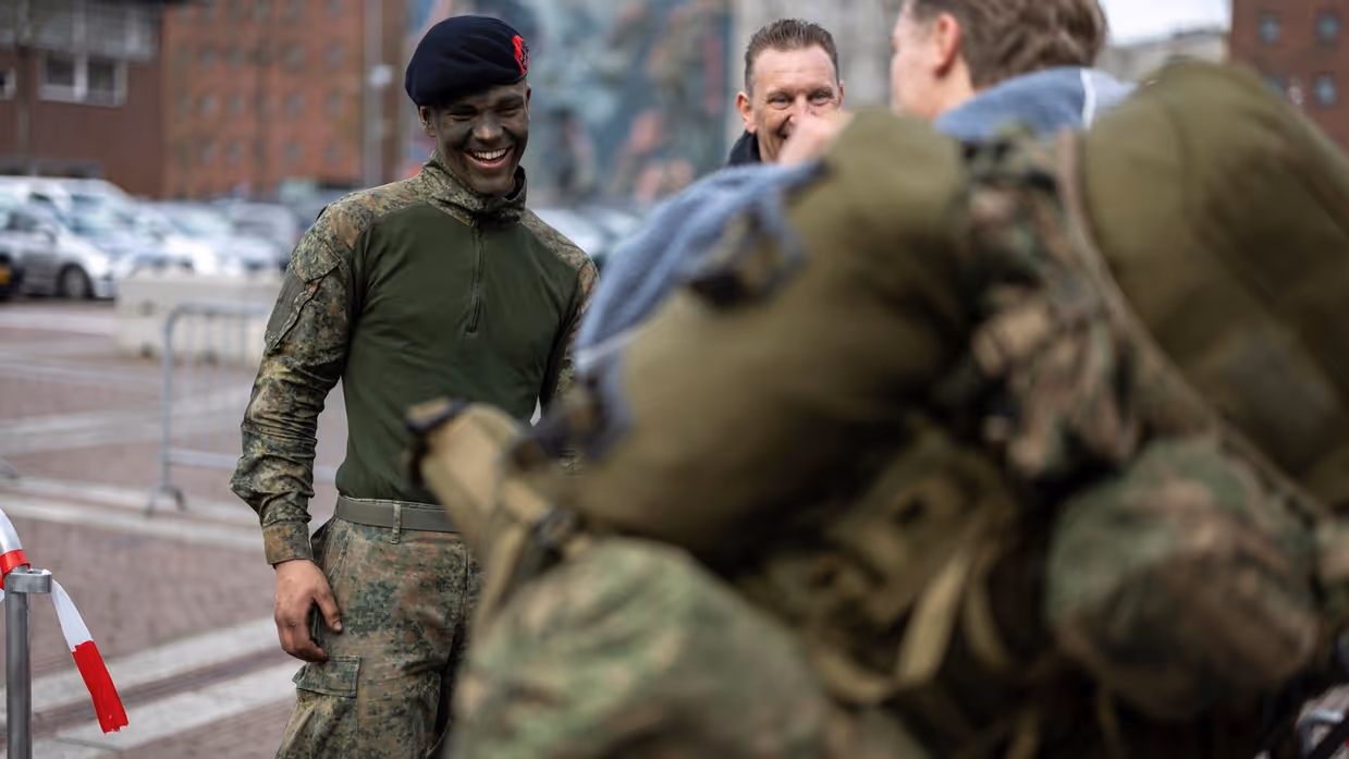 Marinier 1 Timo en zijn oom staan te lachen terwijl Timo’s makker zijn rugzak probeert op te tillen. 