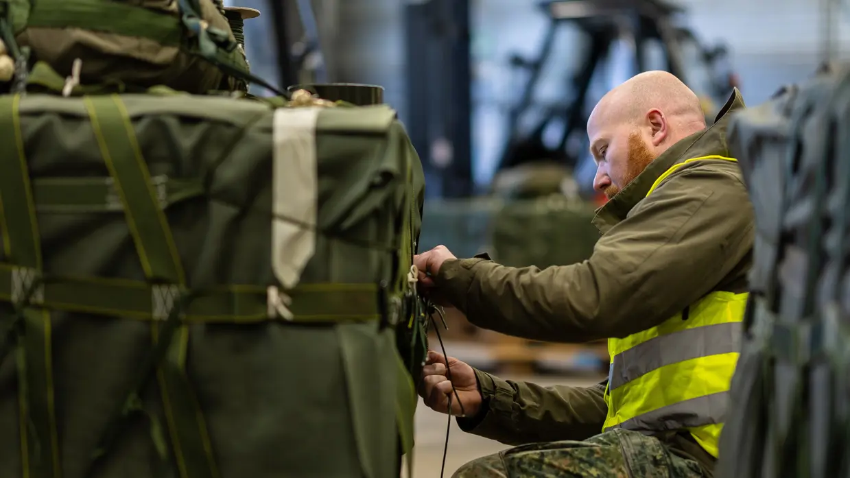 Een militair is bezig met het insnoeren van een groene vrachtbundel.