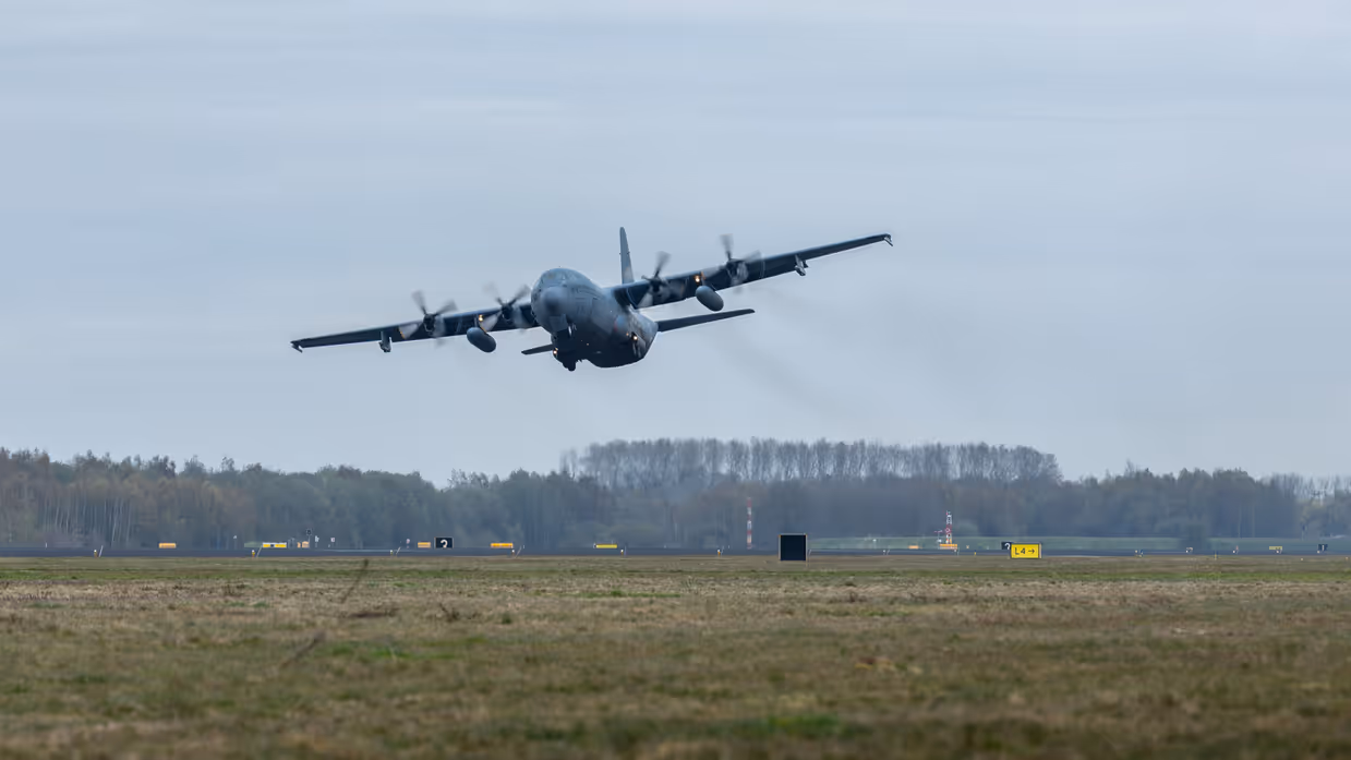Een transportvliegtuig stijgt op, het landingsgestel is nog nét uitgeklapt.