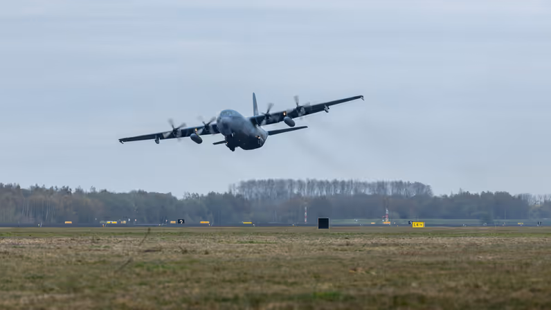 Een transportvliegtuig stijgt op, het landingsgestel is nog nét uitgeklapt.