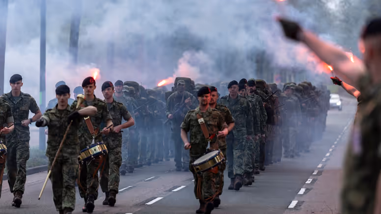 De nieuwe mariniers en hun kader komen aanmarcheren terwijl rode fakkels zijn ontstoken. 