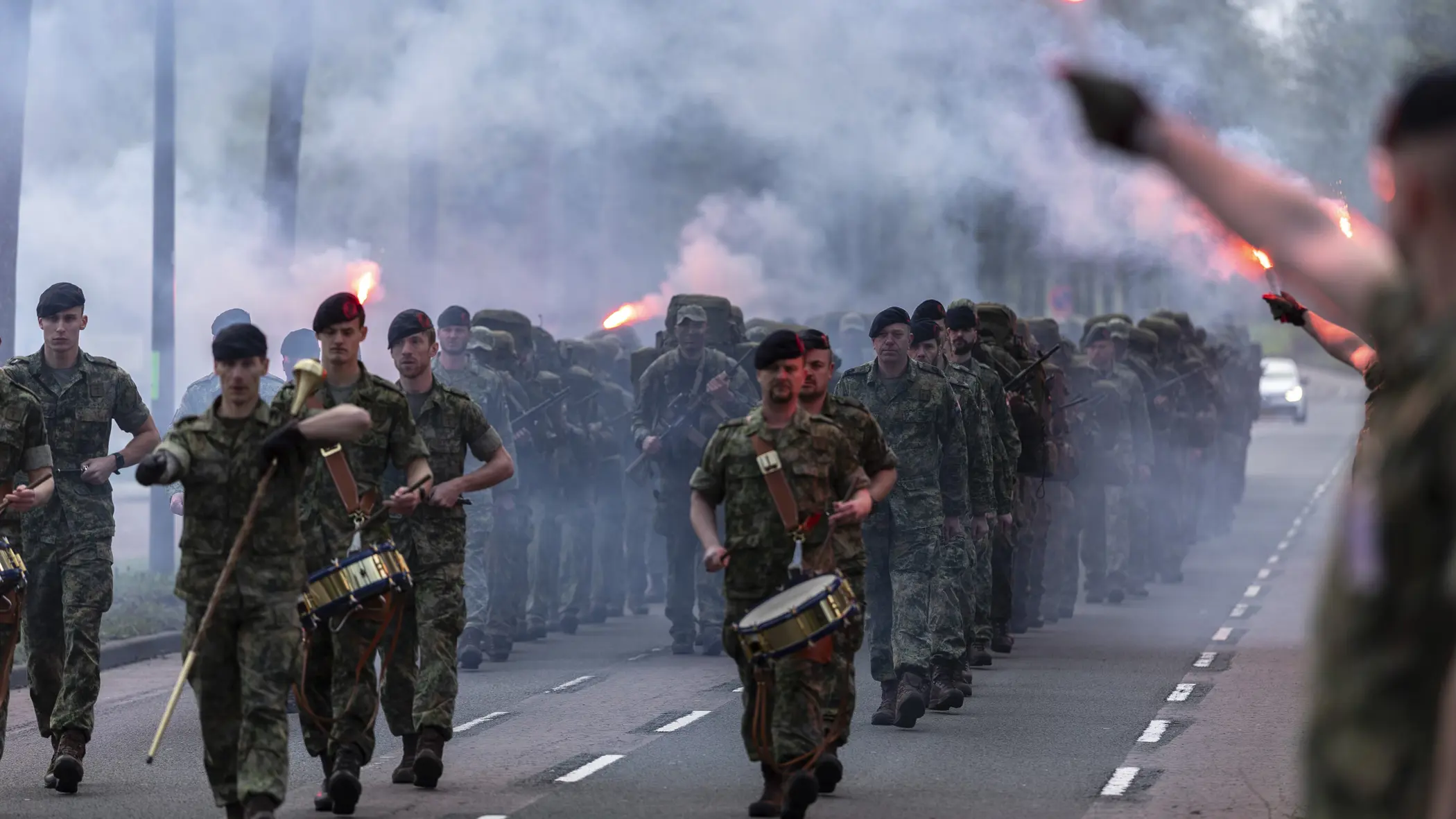 De nieuwe mariniers en hun kader komen aanmarcheren terwijl rode fakkels zijn ontstoken. 