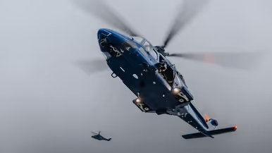 Alt: Op de linkerfoto klimt een militair aan boord, terwijl een collega dekking geeft. Rechts hangt een blauwe politiehelikopter stil boven het schip om operators af te zetten aan boord. 
