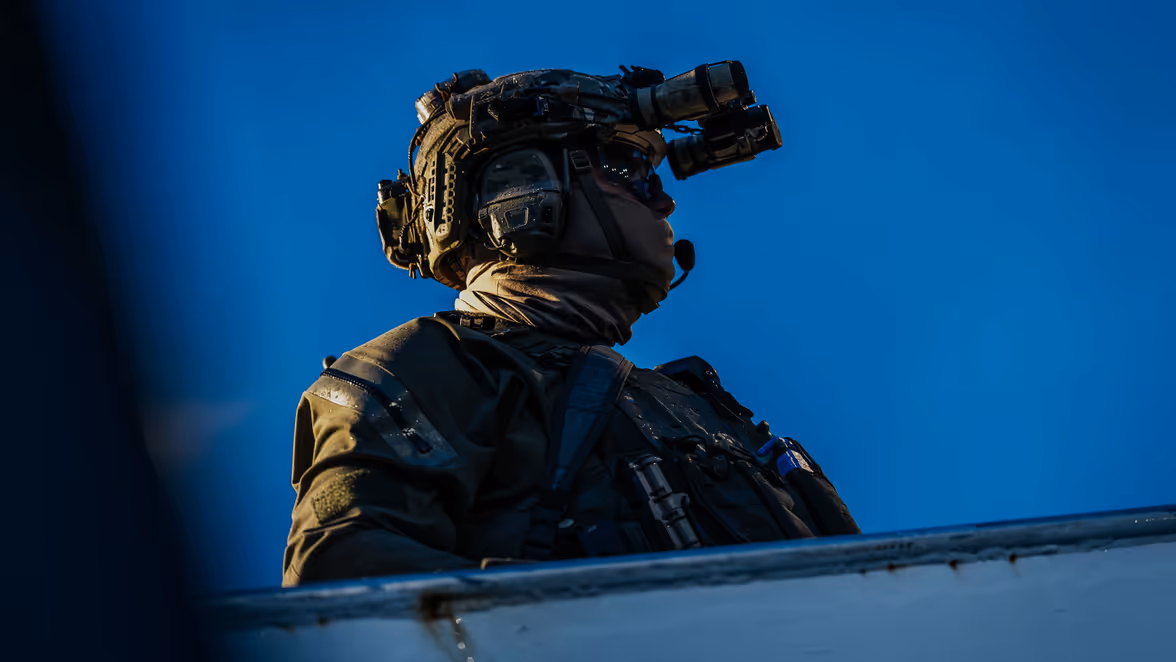 Close-up van een operator tegen een blauwe avondlucht. Op zijn helm draagt hij nachtzichtapparatuur. 