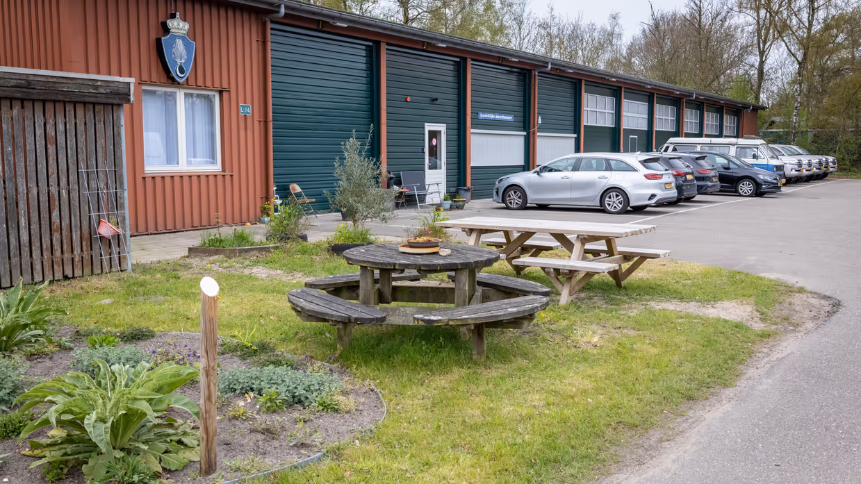 Loods met geparkeerde voertuigen ervoor.