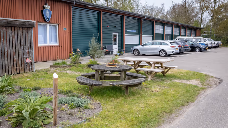 Loods met geparkeerde voertuigen ervoor.