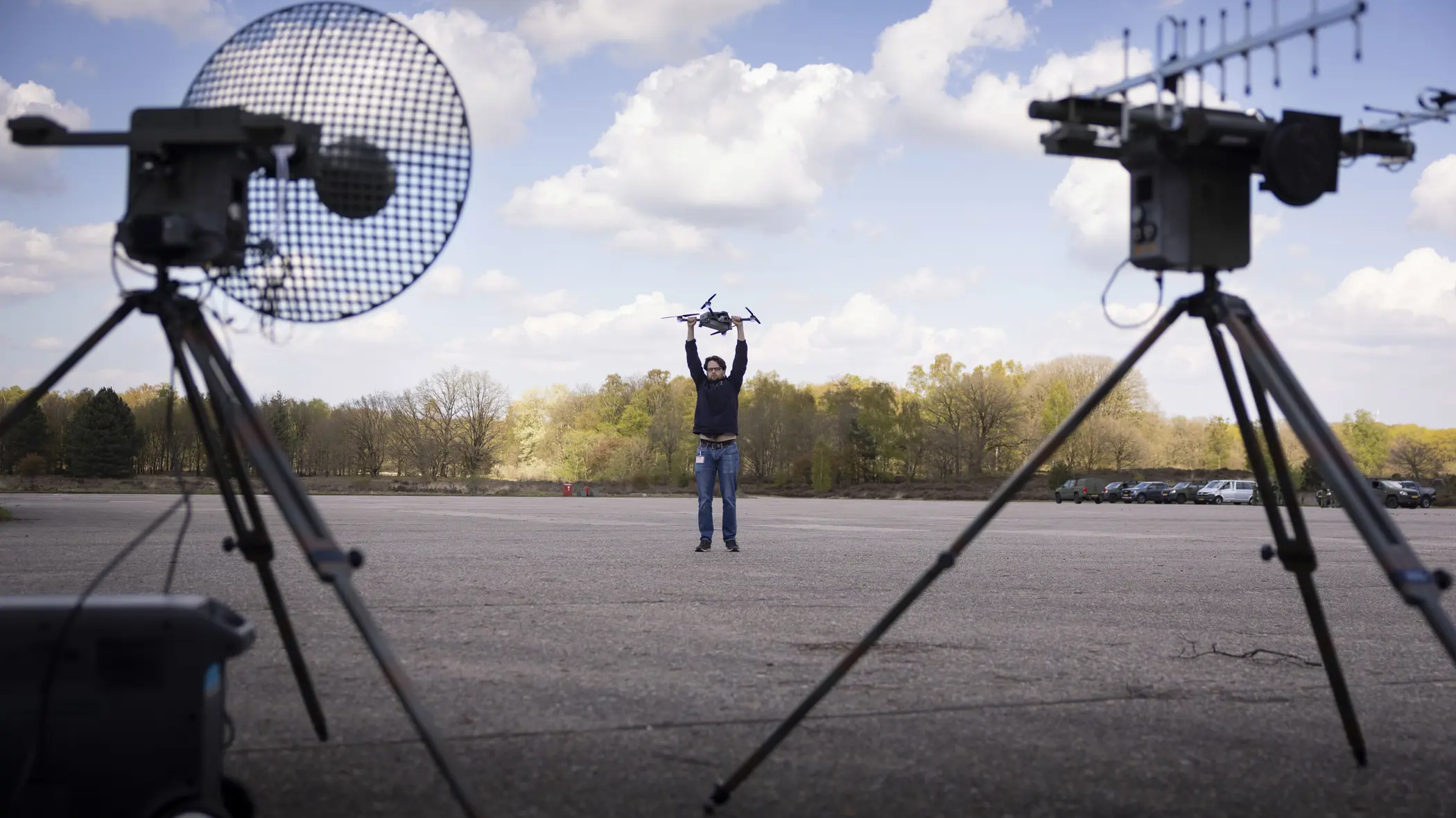 Personeel staande bij de Tracking Antenna Rotators met een drone hoverend op de voorgrond. 