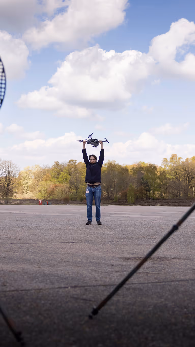Personeel staande bij de Tracking Antenna Rotators met een drone hoverend op de voorgrond. 