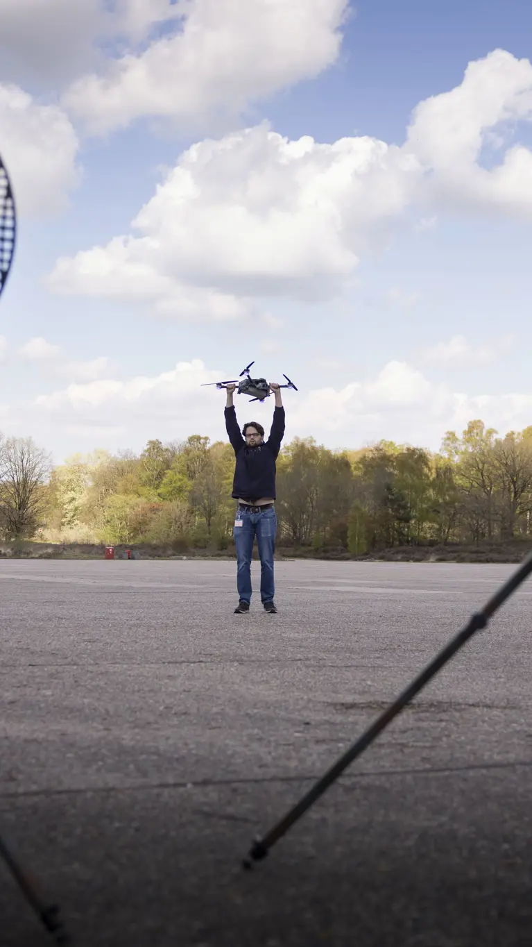 Personeel staande bij de Tracking Antenna Rotators met een drone hoverend op de voorgrond. 