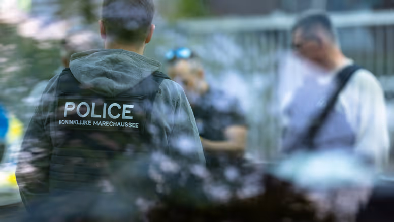 Een marechaussee in burger met een KMar-vest aan. 