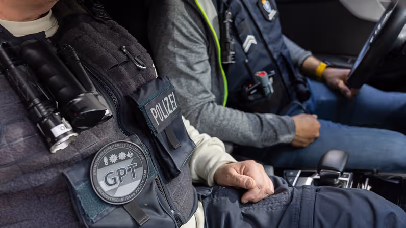 Een Duitse en een Nederlandse collega van het GPT zitten in een onopvallende auto. 