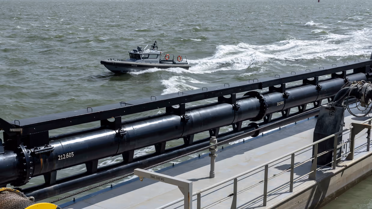 Een rhib-boot van de Koninklijke Marechaussee vaart naast een grote boot.