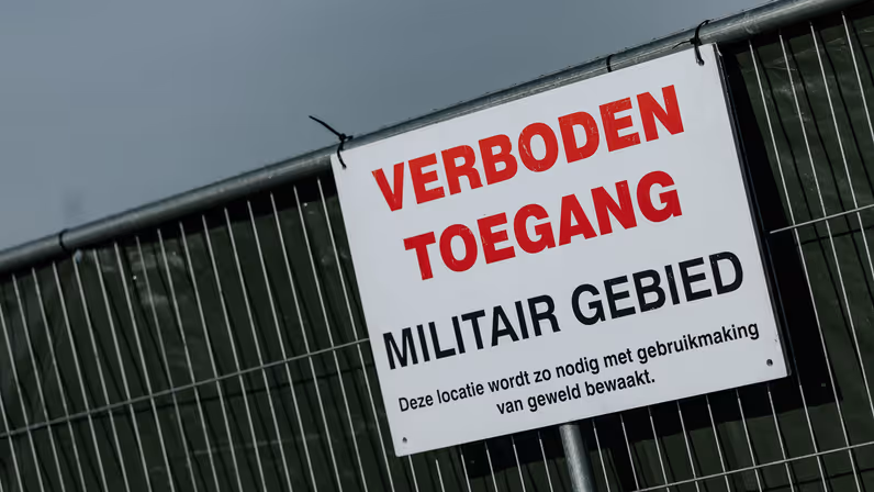 Een wit bord met de tekst: verboden toegang, militair geweld.  