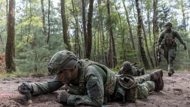 Militairen liggen op hun buik en vegen een mijn af.