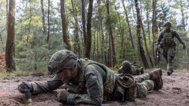 Militairen liggen op hun buik en vegen een mijn af.