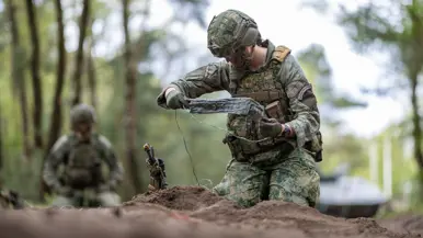 Een militair bevestigt een haak aan een mijn.