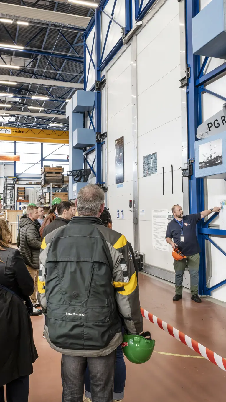 Groep mensen krijgt rondleiding door werkplaats marine.
