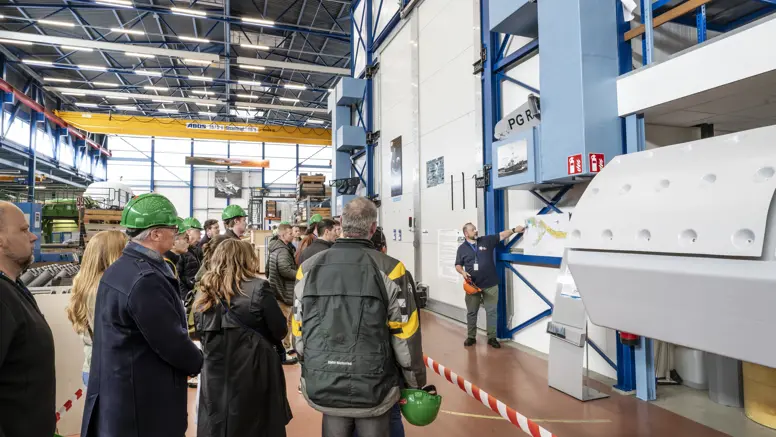 Groep mensen krijgt rondleiding door werkplaats marine.