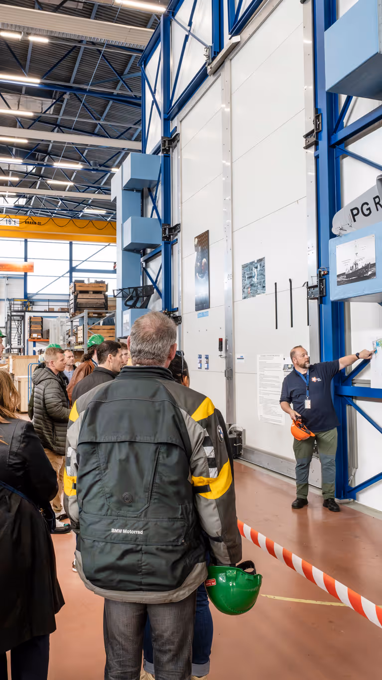 Groep mensen krijgt rondleiding door werkplaats marine.