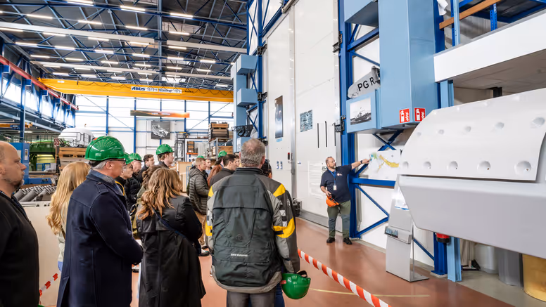 Groep mensen krijgt rondleiding door werkplaats marine.