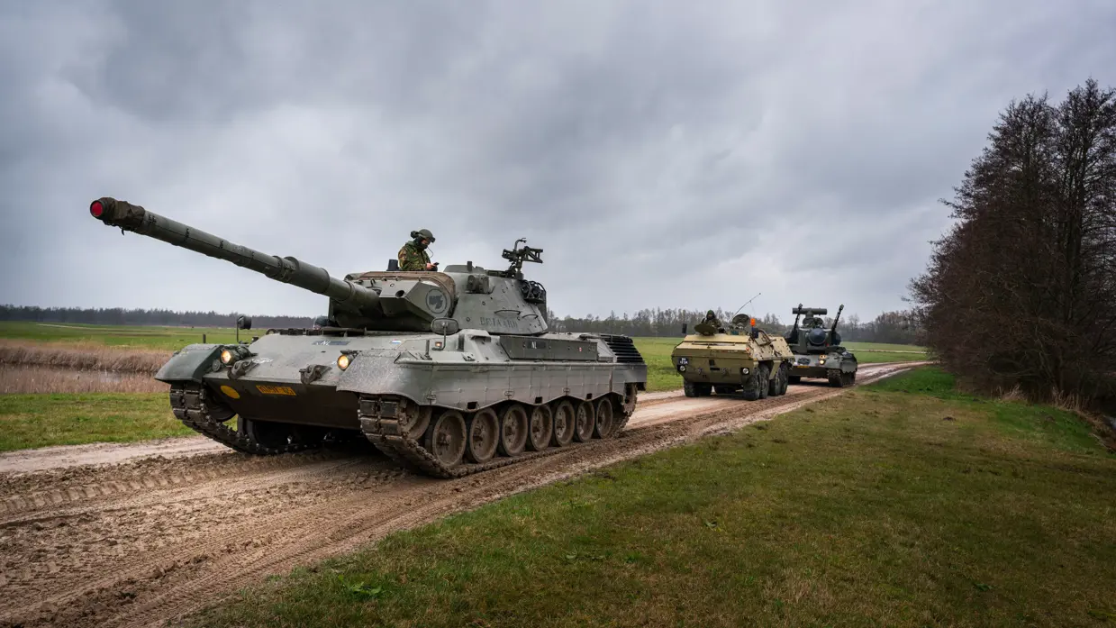 Een drietal tanks rijdt over een pad achter elkaar.