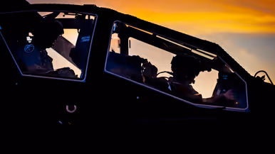Een militaire helikopter staat stil in een veld, terwijl twee soldaten bij een groene terreinwagen met open laadbak staan. Rechts: het interieur van een helikopter tijdens zonsondergang. Twee piloten zitten in de cockpit, omlijst door oranje en donkere kleuren aan de lucht. 
