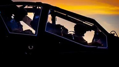 Een militaire helikopter staat stil in een veld, terwijl twee soldaten bij een groene terreinwagen met open laadbak staan. Rechts: het interieur van een helikopter tijdens zonsondergang. Twee piloten zitten in de cockpit, omlijst door oranje en donkere kleuren aan de lucht. 