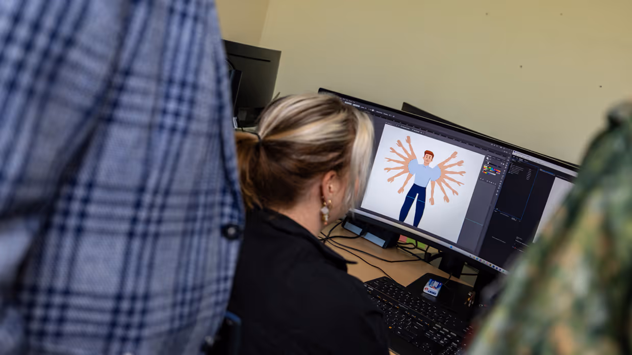 Een jonge vrouw kijkt naar een computerscherm. Op het scherm is een marechausseepoppetje te zien met zijn armen in verschillende posities.