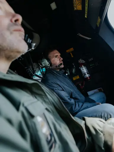  Boswijk naar buiten kijkend in een vliegende helikopter.