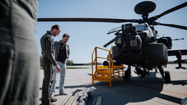  Boswijk krijgt uitleg van een militair over de verschillende soorten munitie en bewapening die uitgestald op de grond liggen voor een Apache.