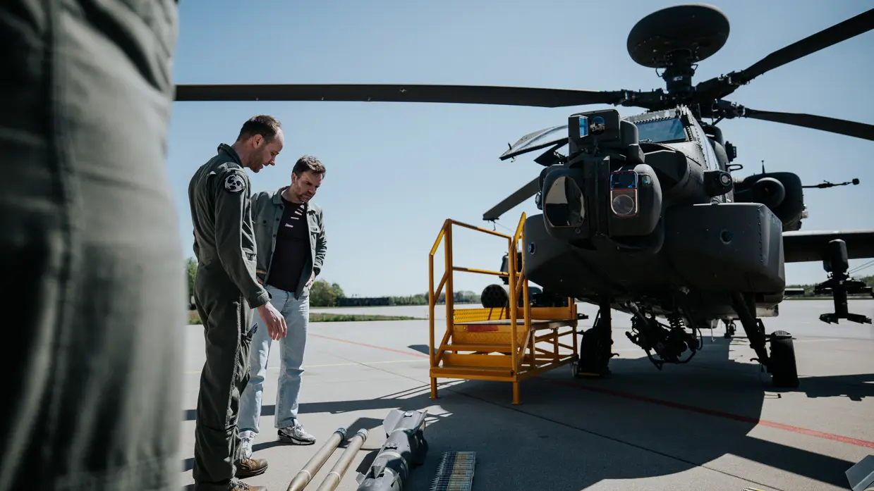  Boswijk krijgt uitleg van een militair over de verschillende soorten munitie en bewapening die uitgestald op de grond liggen voor een Apache.
