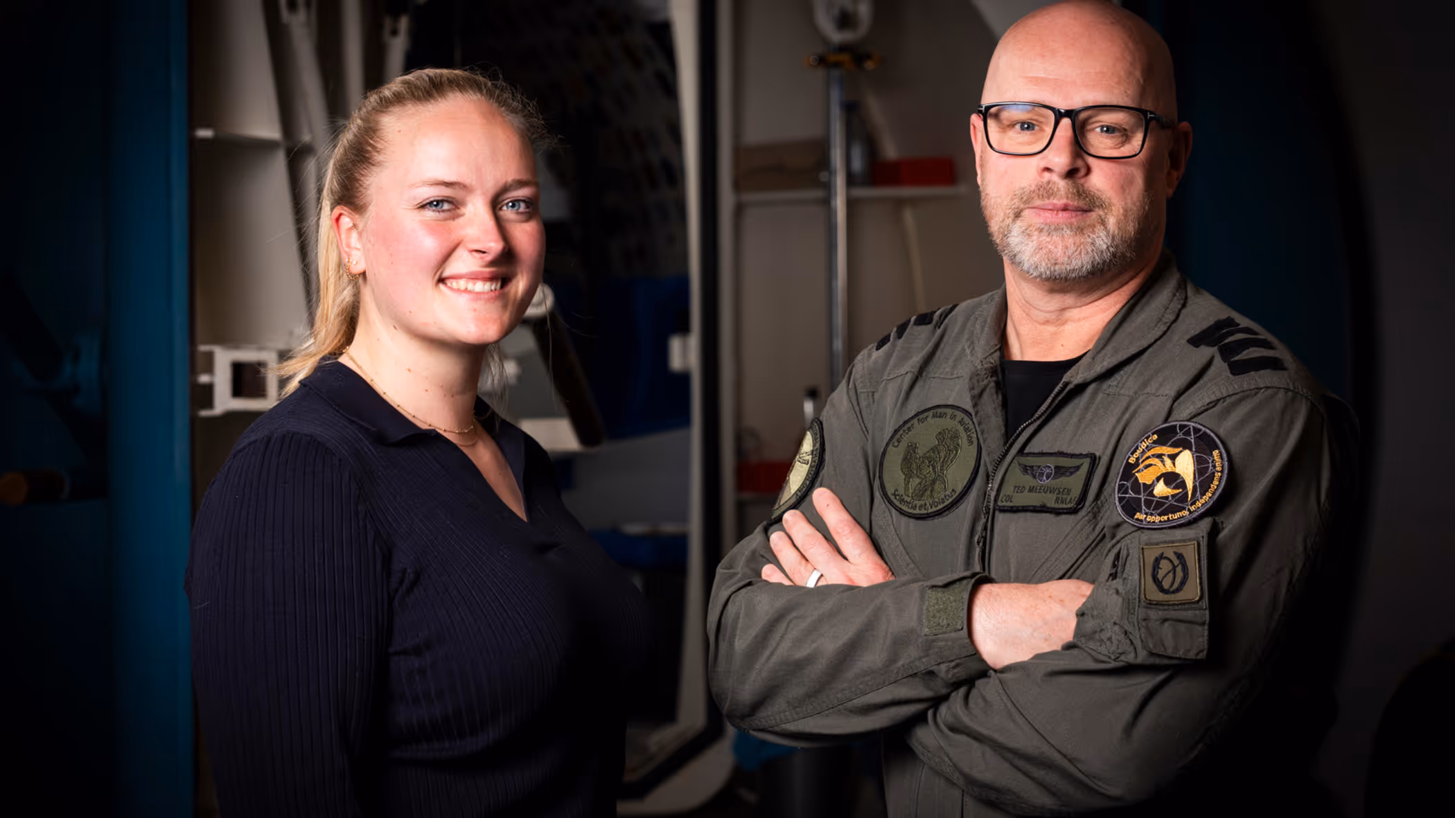 Vrouw in burgerkleding en man in militair uniform staan naast elkaar. 