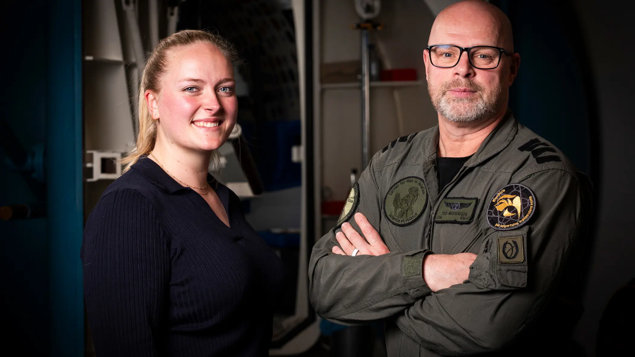 Vrouw in burgerkleding en man in militair uniform staan naast elkaar. 