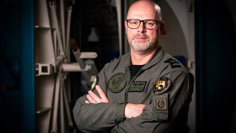 Militair met baard en bril kijkt vriendelijk in de camera. 