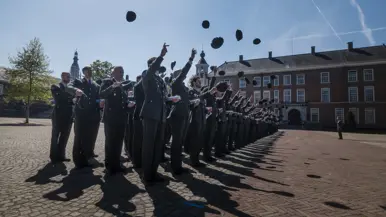 Nieuwe officieren gooien hun pet in de lucht.