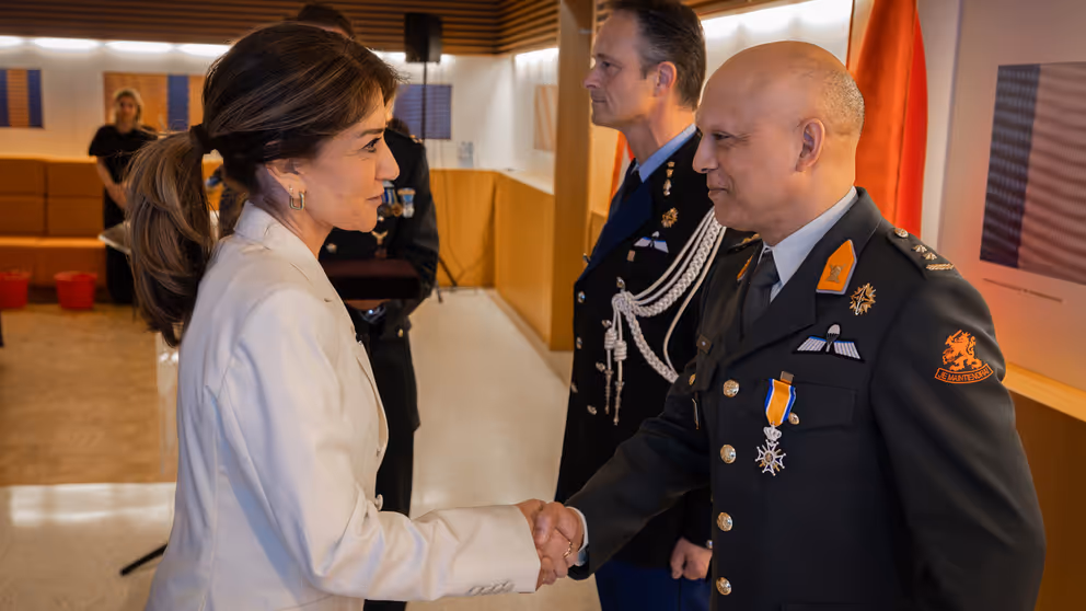 Minister van Defensie schudt de hand van gedecoreerden.