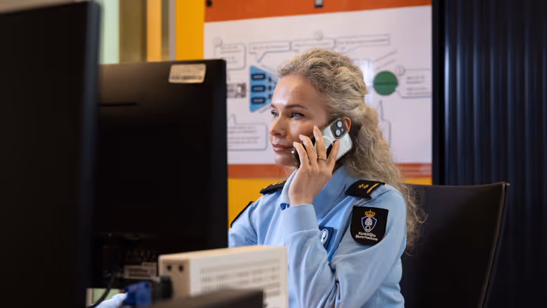 Luitenant-kolonel Irena zit achter een computer en houdt een telefoon bij haar oor.