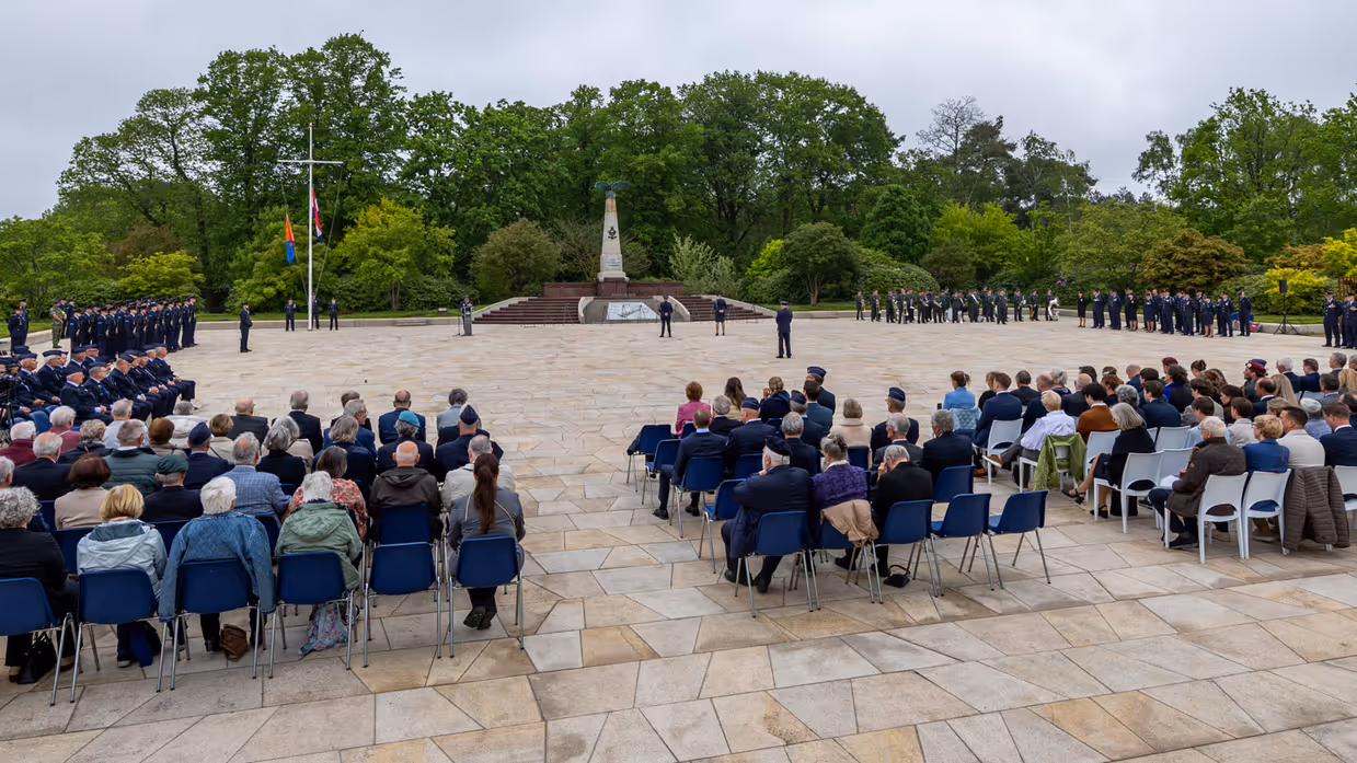 Overzicht van de herdenkingsplaats op de voormalige vliegbasis Soesterberg met in het midden het monument, links en rechts opgestelde luchtmachtmilitairen en in de voorgrond genodigden. 
