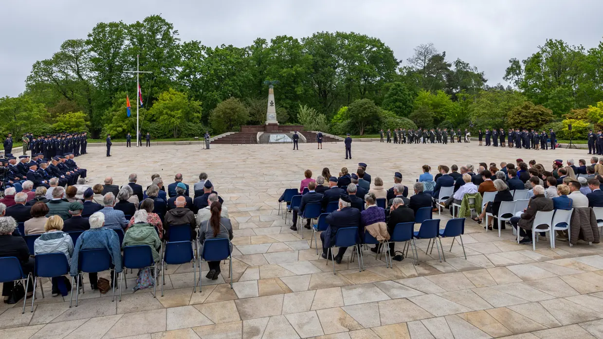 Overzicht van de herdenkingsplaats op de voormalige vliegbasis Soesterberg met in het midden het monument, links en rechts opgestelde luchtmachtmilitairen en in de voorgrond genodigden. 