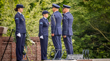 Twee militairen salueren tegenover een krans op een standaard. Daarnaast staan twee andere militairen.